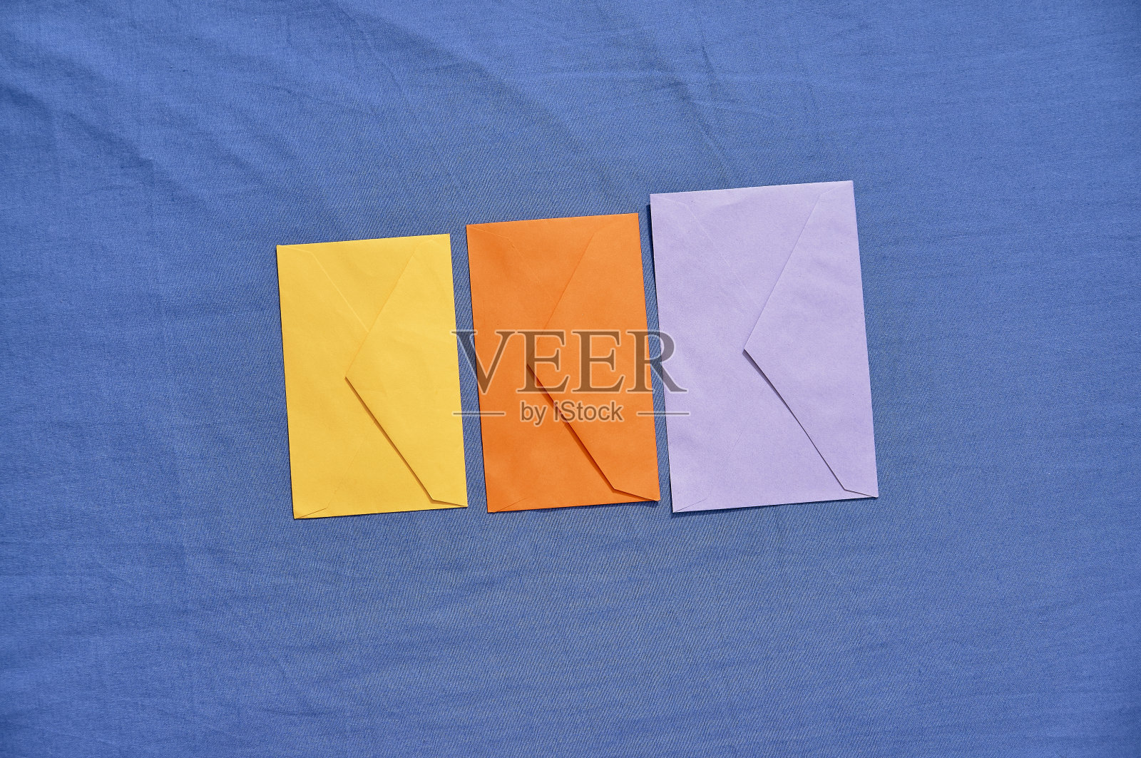 黄色，橙色和紫色信封上的蓝色背景照片摄影图片