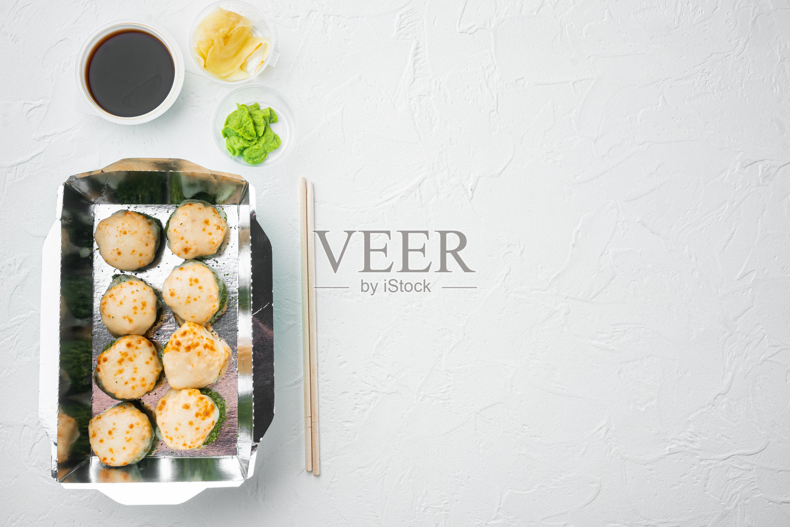 寿司卷在外卖容器中，白色的石头背景上，俯视图平铺，有拷贝空间和文字空间照片摄影图片