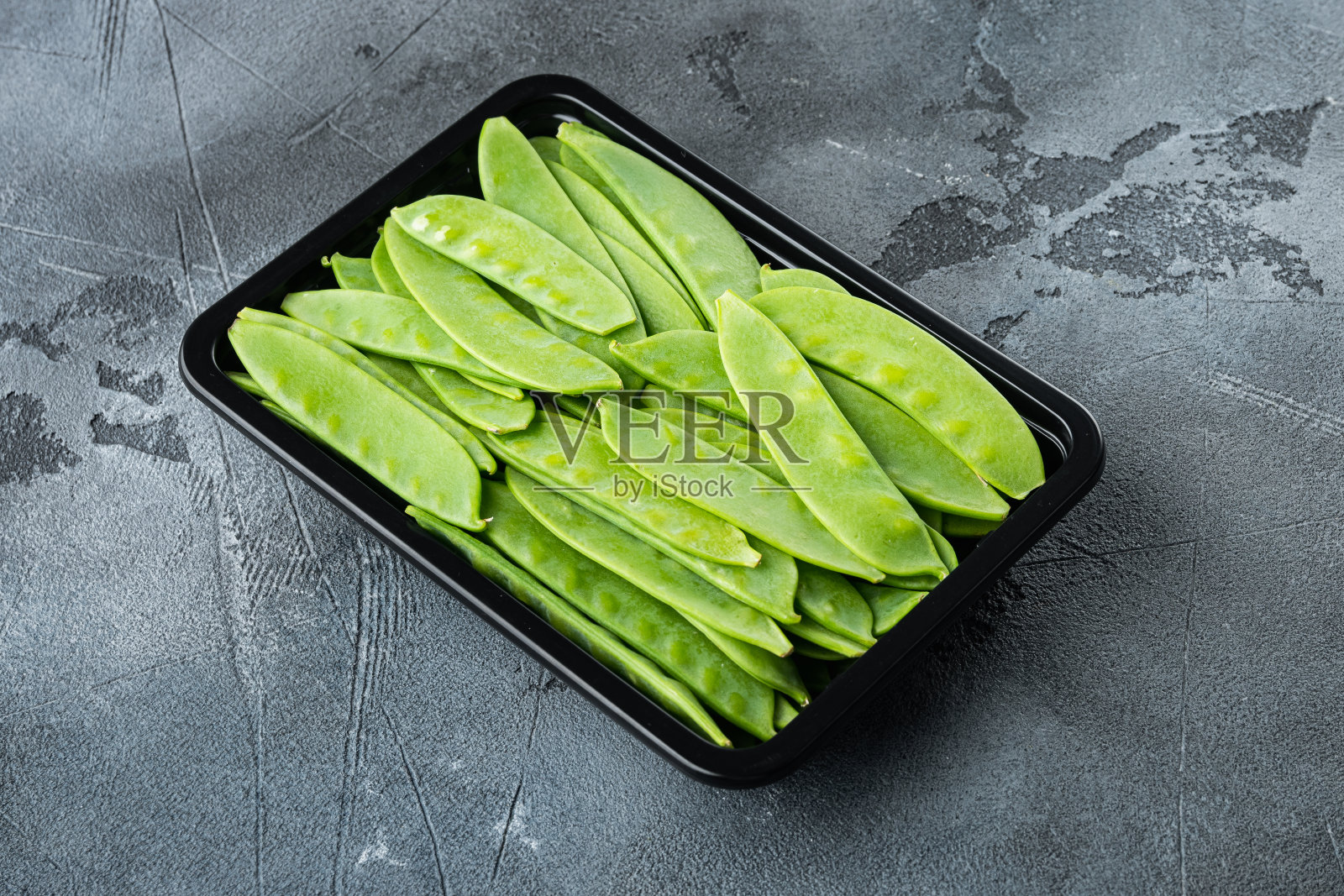 新鲜的有机芒果，也被称为糖豆，在塑料容器，在灰色的石头背景照片摄影图片