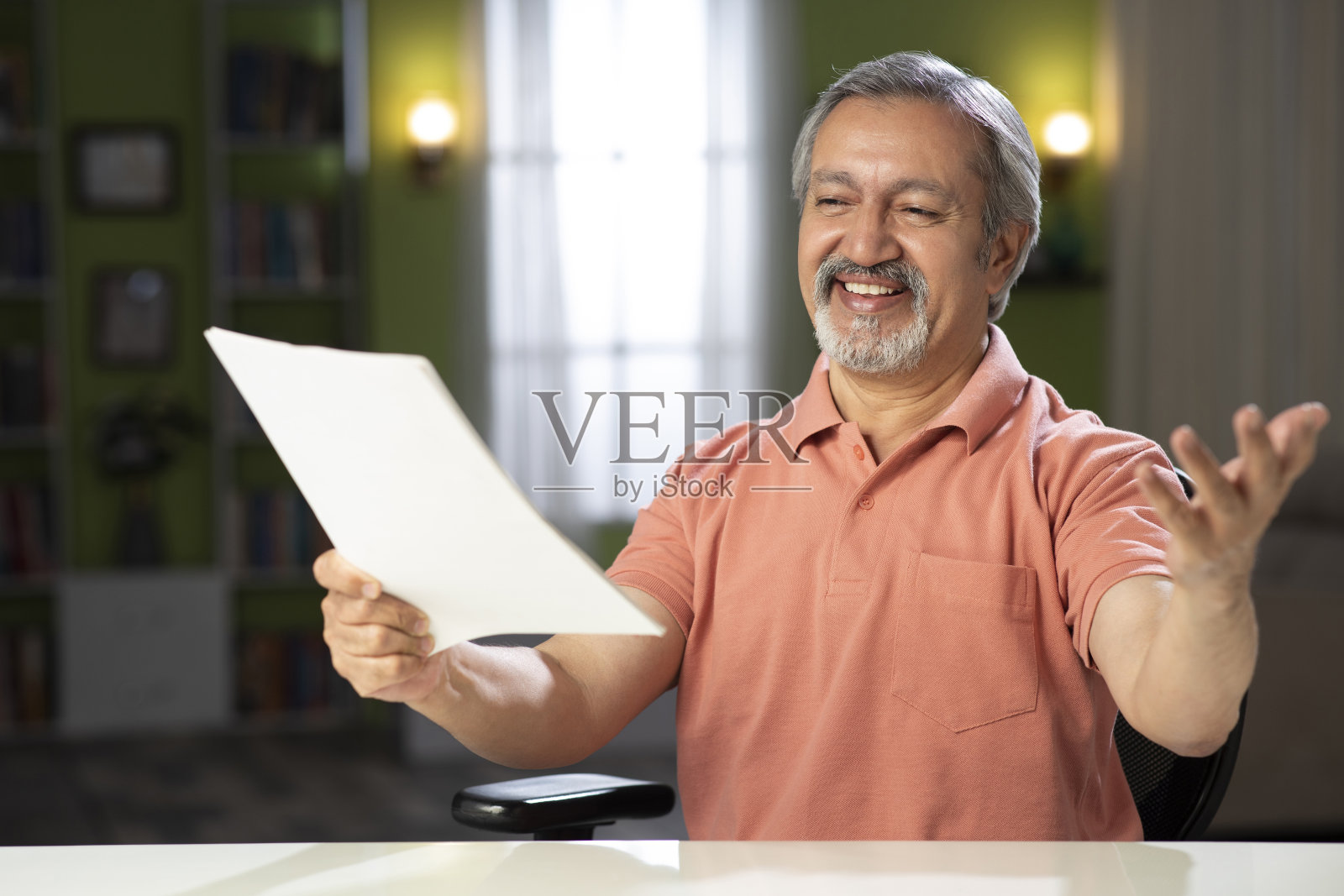 一个成熟男人坐在家里的椅子上的照片:-库存照片照片摄影图片