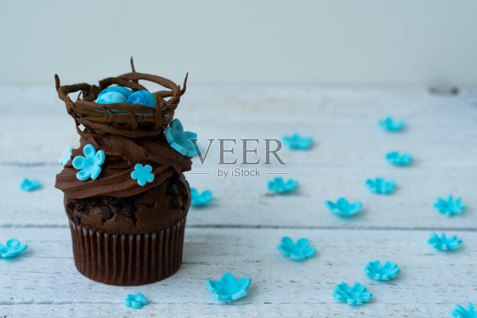 有巧克力巢和装饰蛋的复活节巧克力纸杯蛋糕。春天的花。乡村木背景照片摄影图片