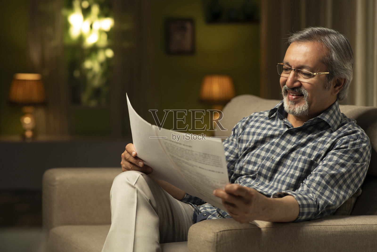 中年男人在家坐在沙发上看文件照片摄影图片