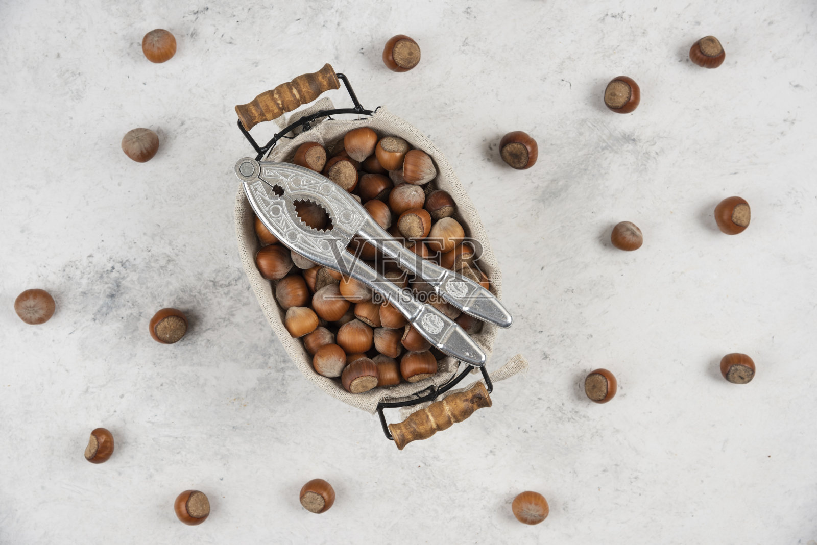 篮子的榛子壳和坚果开裂工具在大理石的背景照片摄影图片