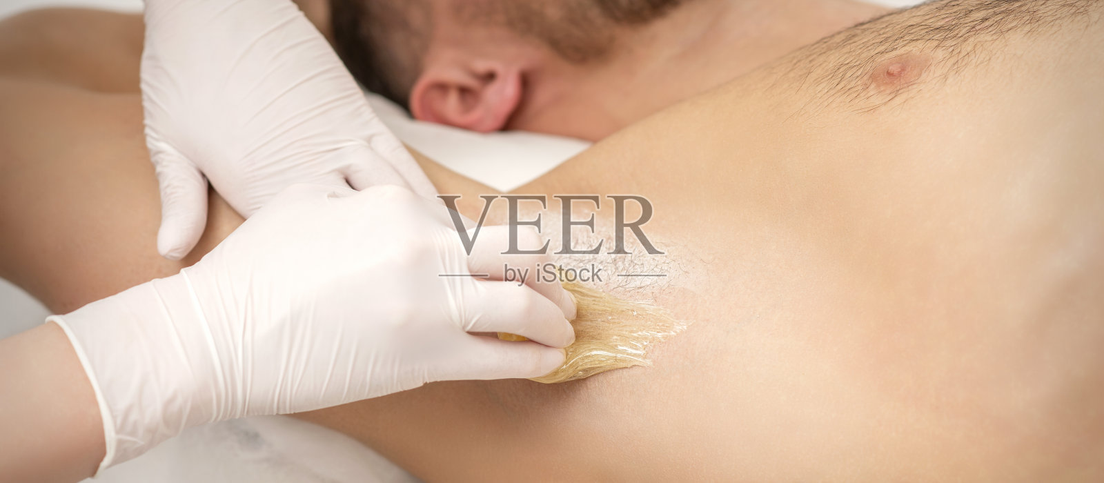 美容师给年轻男性腋窝脱毛照片摄影图片