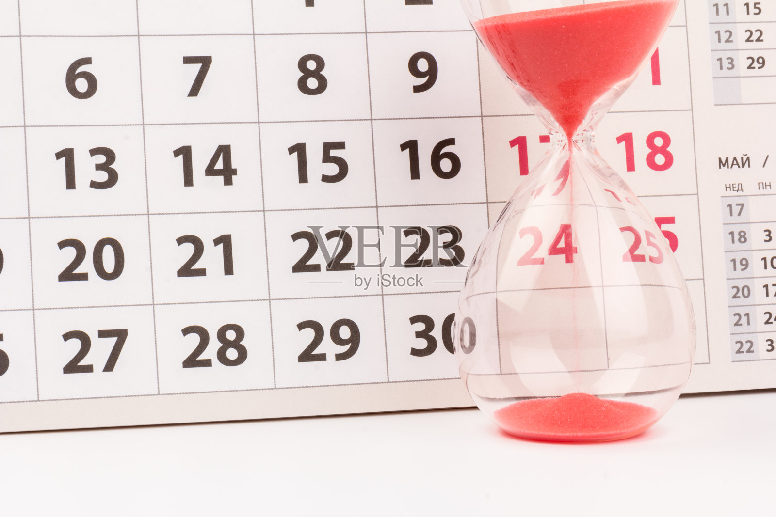 时间的流逝的概念。水晶沙漏与红色的沙子和日历在光的背景照片摄影图片