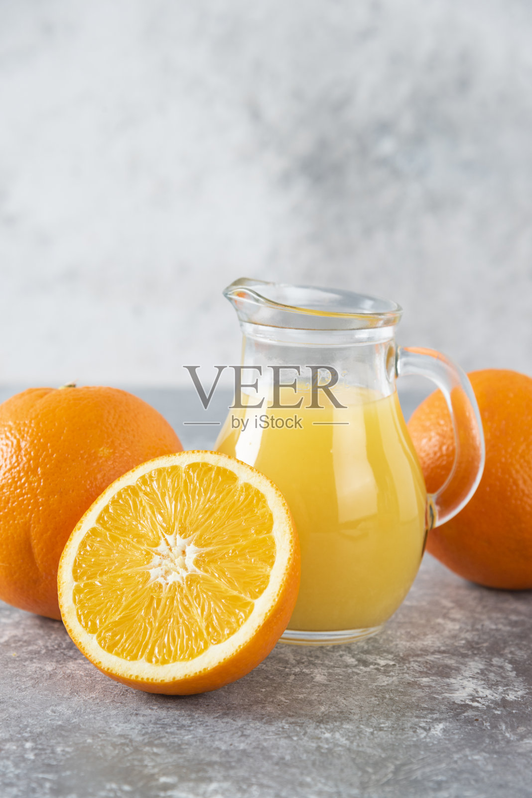 一个玻璃罐的果汁与新鲜的橘子水果在石头的背景照片摄影图片