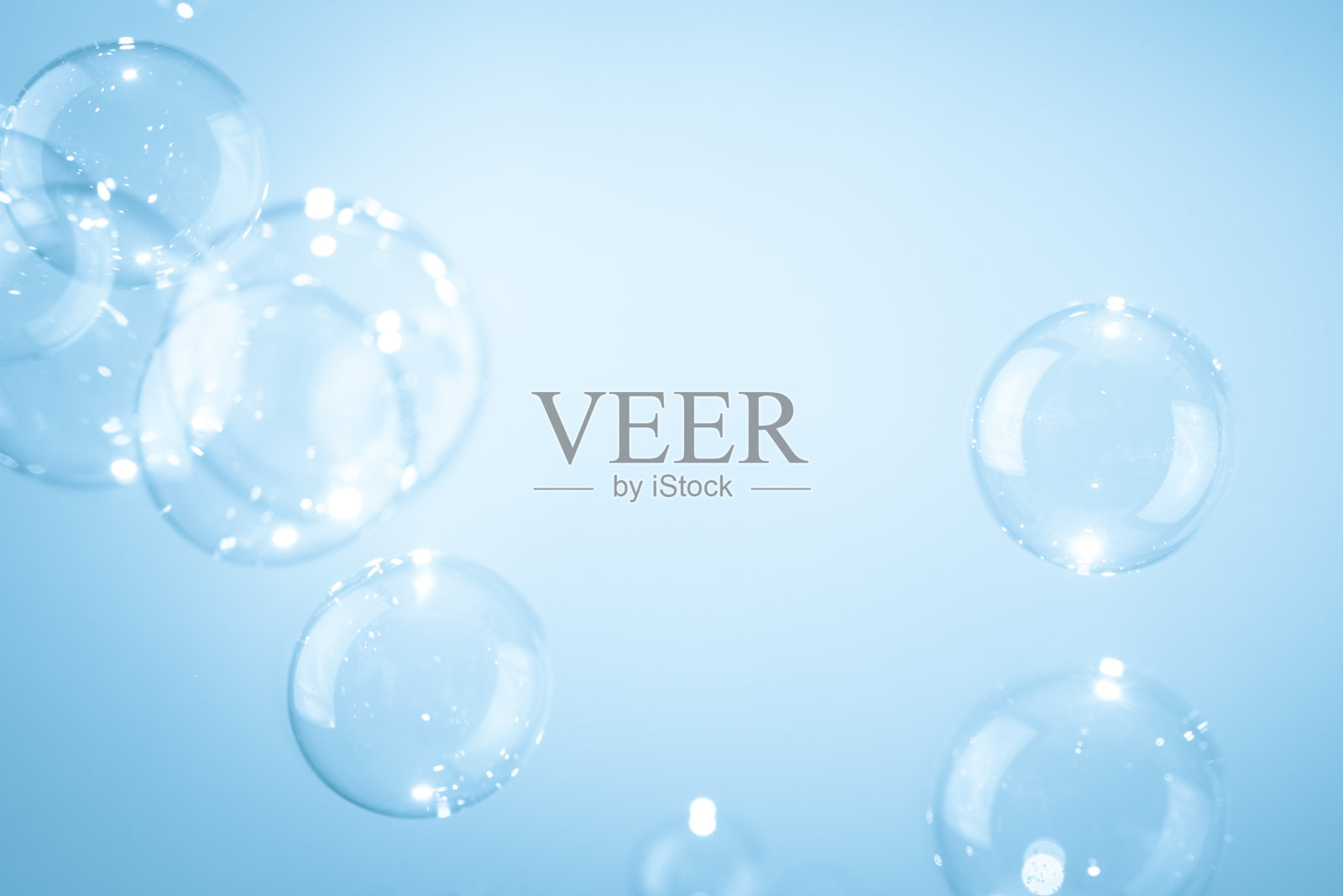 美丽闪亮透明的肥皂泡漂浮在蓝色背景上。照片摄影图片