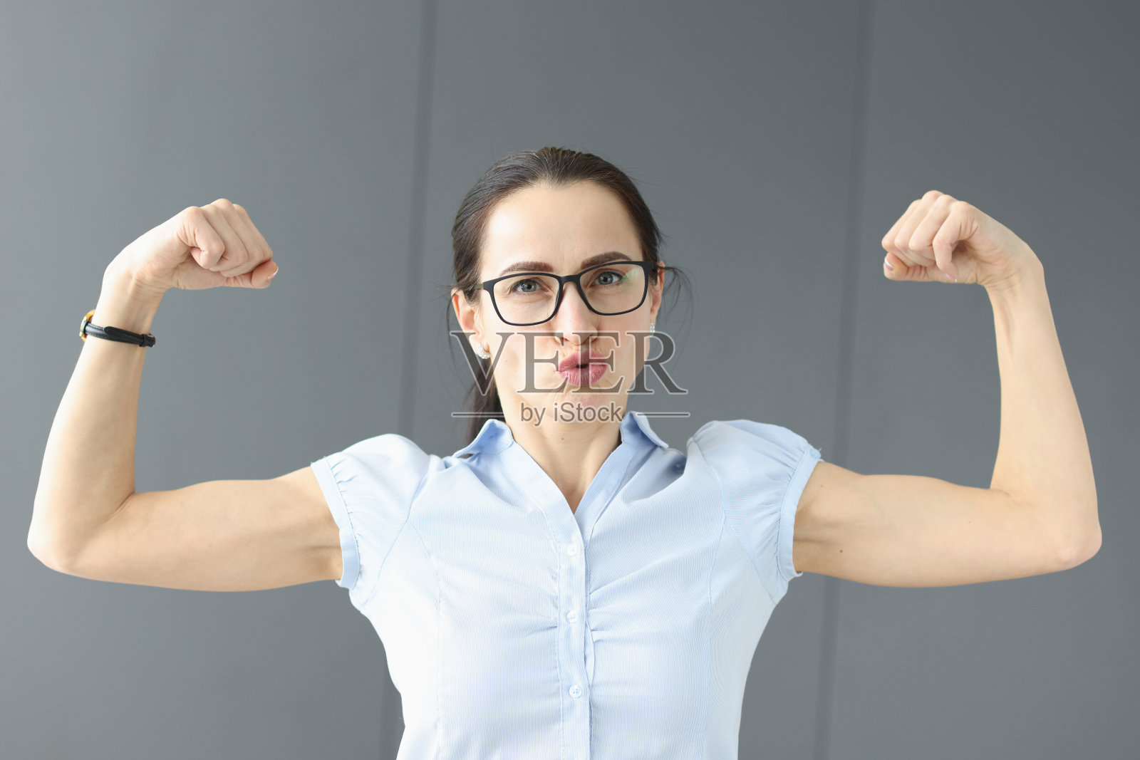 戴着眼镜的年轻女子手臂上的肌肉照片摄影图片