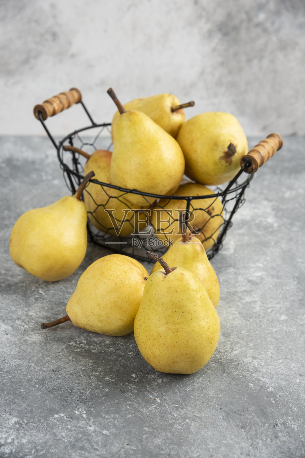 一串新鲜的黄梨放在金属桶里，放在大理石表面照片摄影图片