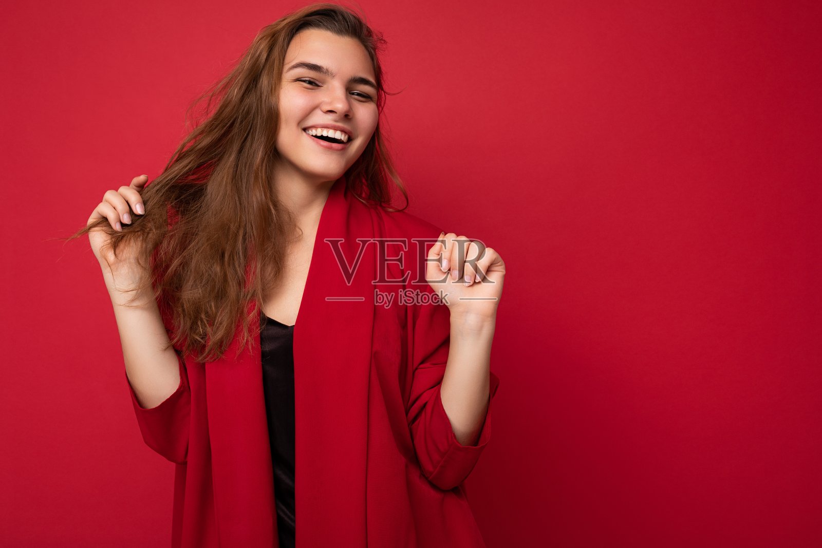 正面开朗的时尚女人的肖像在正装看孤立在红色背景与复制空间的相机照片摄影图片