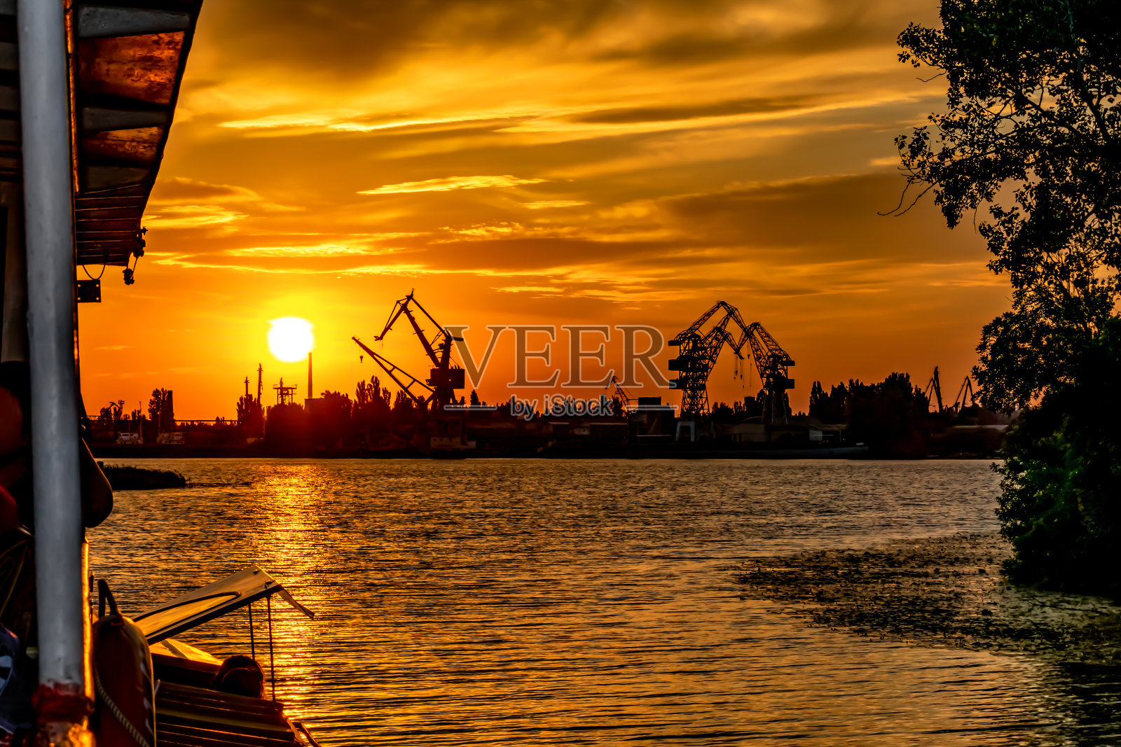 克森(乌克兰)的海岸线剪影和码头上的港口起重机在夕阳的橙色光线中照片摄影图片