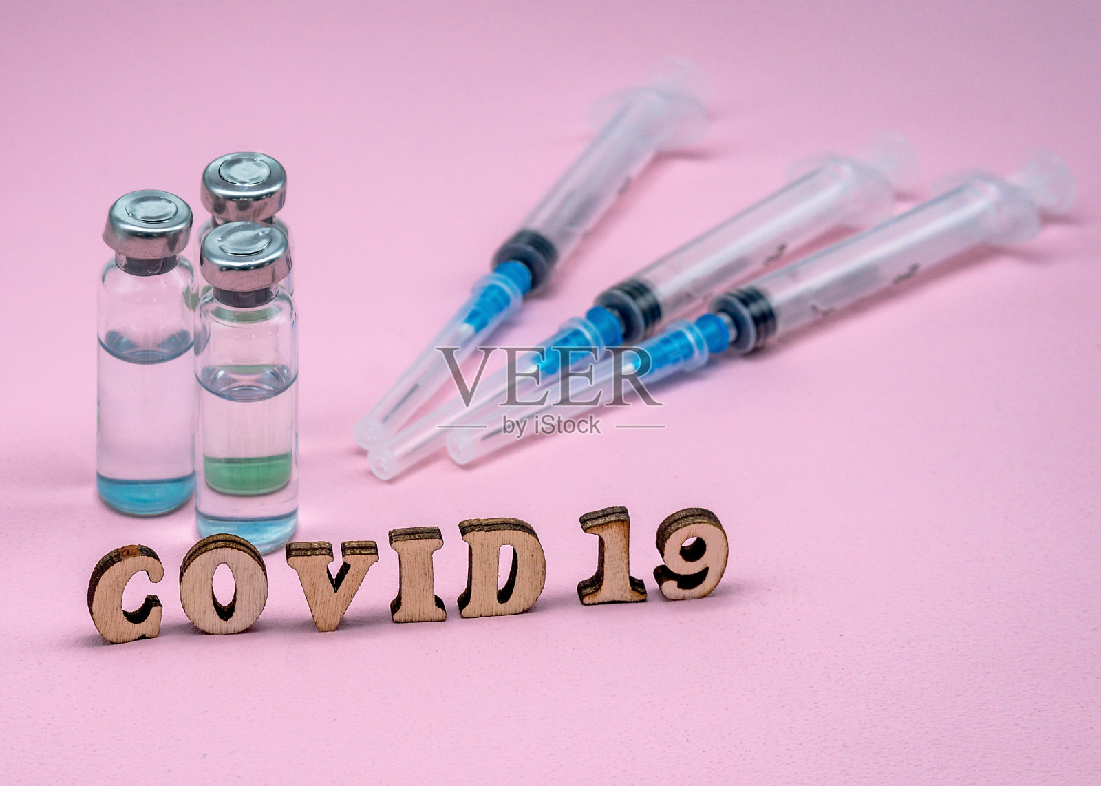 粉红色背景上的医用安瓿和注射器。疫苗接种covid-19。照片摄影图片