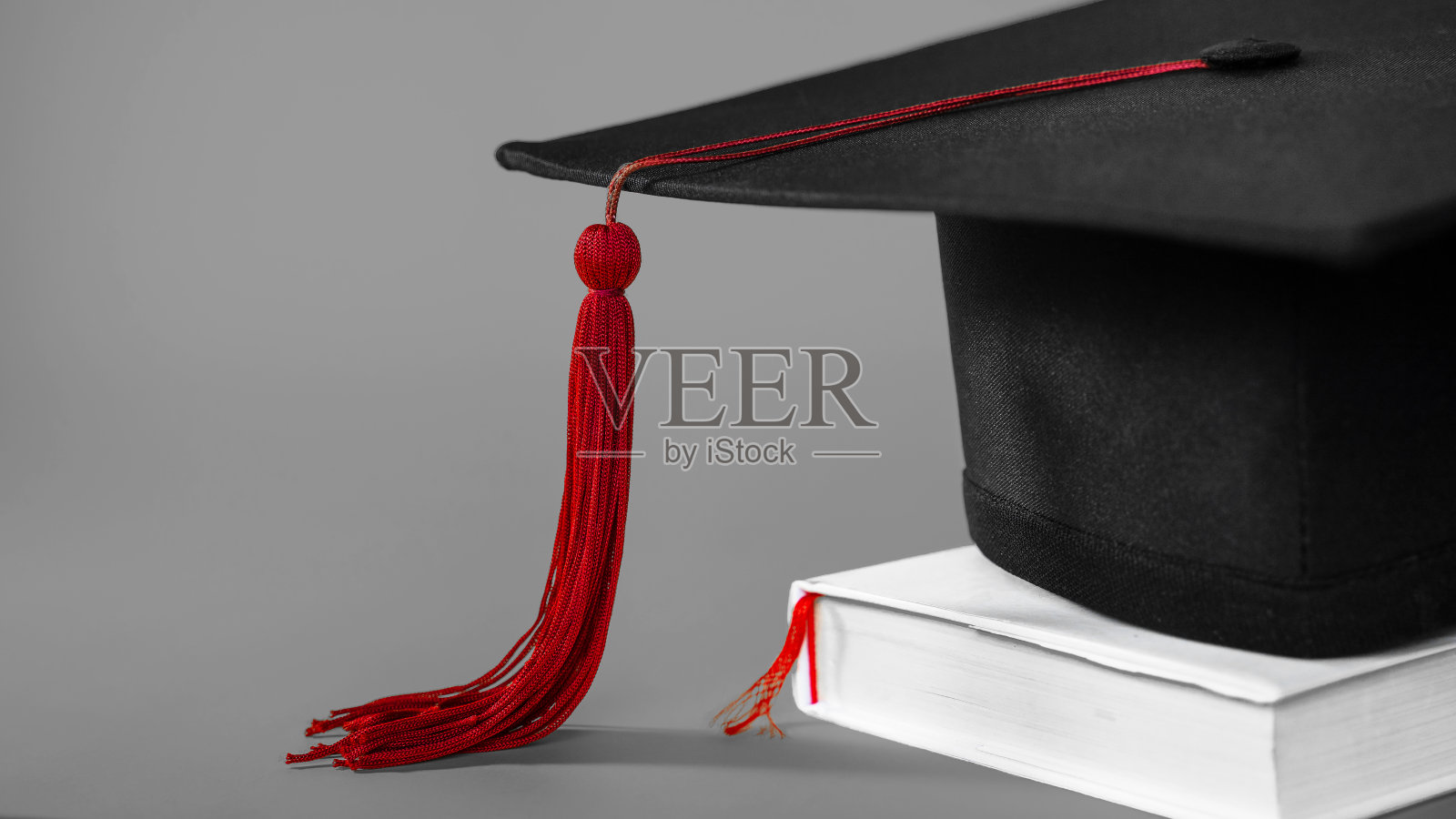 在孤立的灰色背景与空白副本空间左边的学位帽。库存图片照片摄影图片