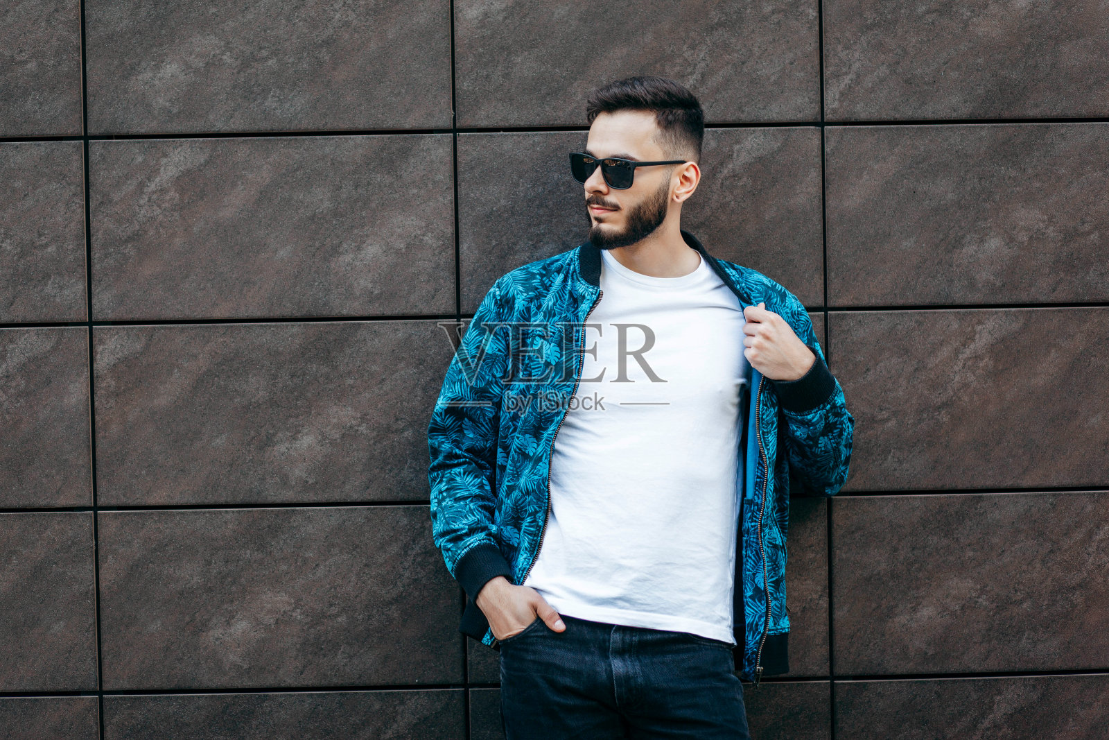 一个留着胡子，穿着白色t恤，戴着眼镜的年轻时髦的男人。街头的照片照片摄影图片