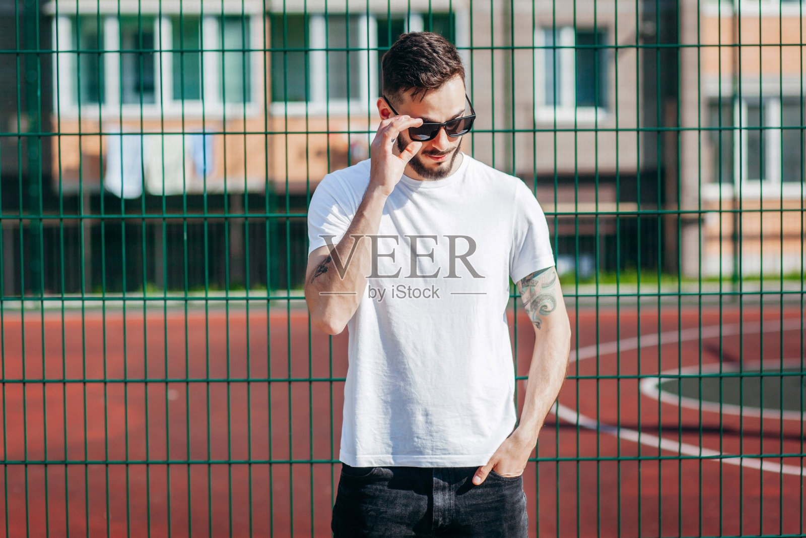 一个留着胡子，穿着白色t恤，戴着眼镜的年轻时髦的男人。街头的照片照片摄影图片