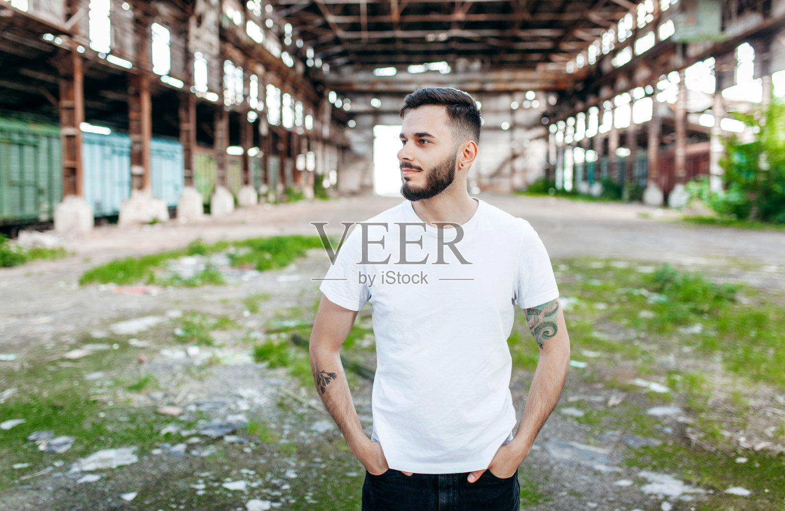 一个留着胡子，穿着白色t恤，戴着眼镜的年轻时髦的男人。街头的照片照片摄影图片