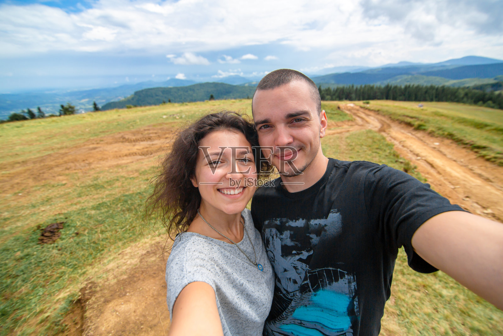 年轻的情侣在令人惊叹的山景背景下拥抱自拍照片摄影图片