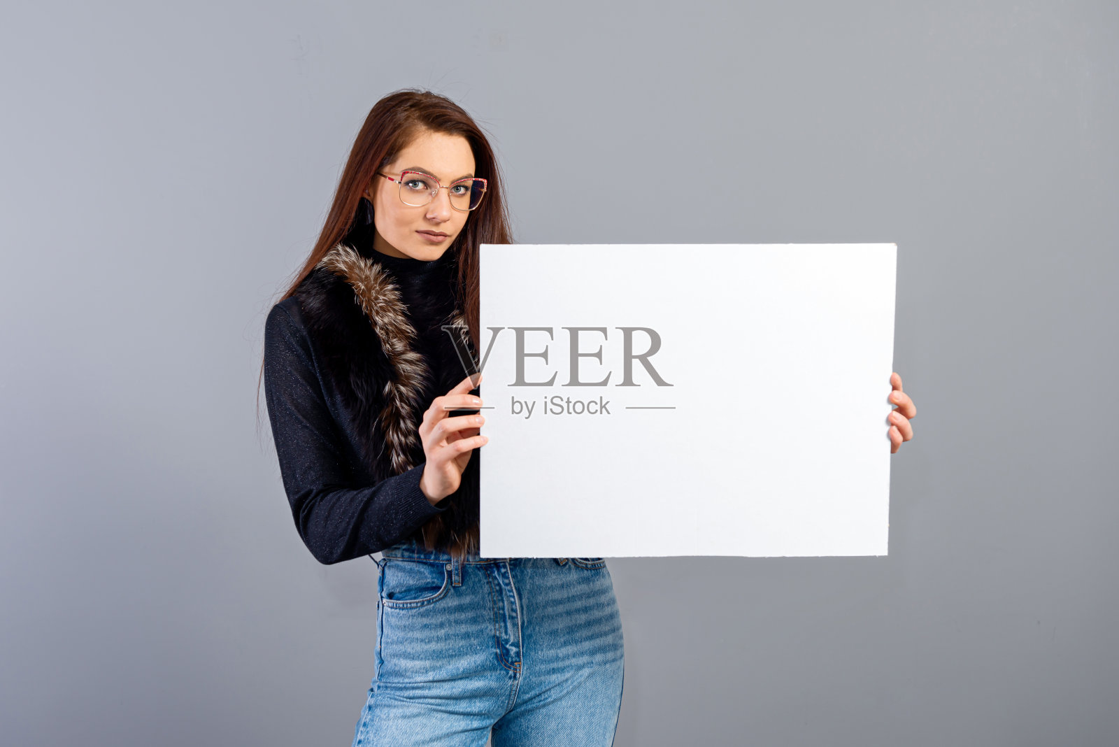 年轻女子的肖像显示空白招牌与拷贝空间，孤立在灰色照片摄影图片