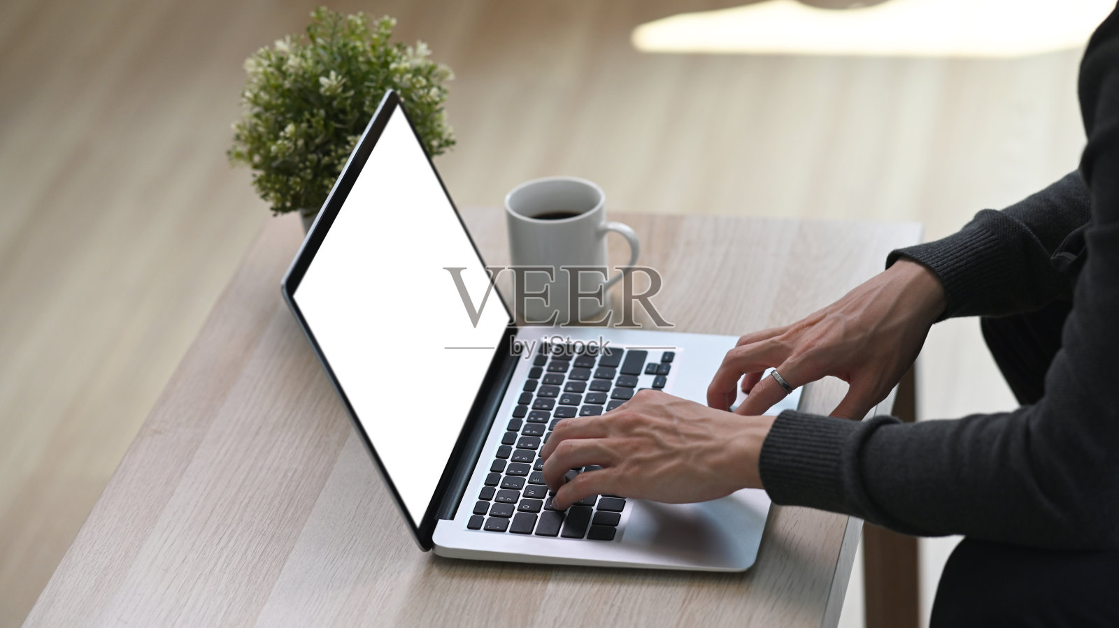 一个年轻人坐在客厅的地板上，在木桌上使用笔记本电脑。照片摄影图片