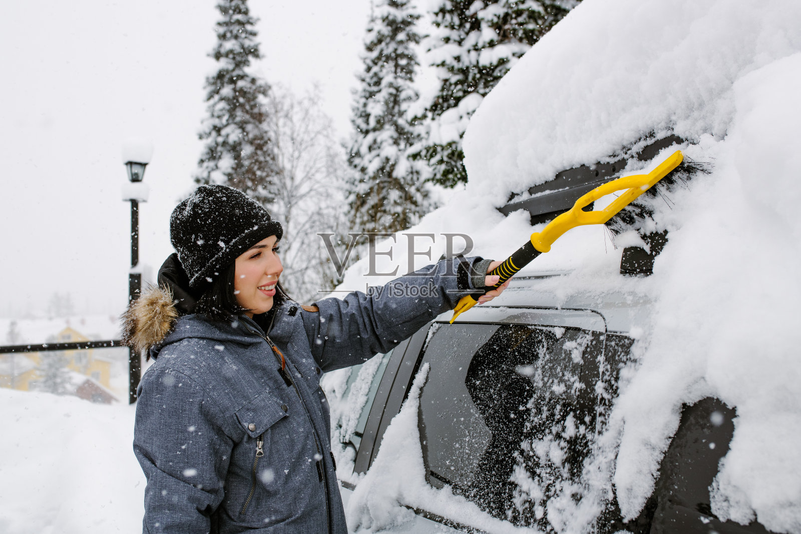 快乐独立的女人在开车前清理她的车。暴风雪在城市的后果照片摄影图片