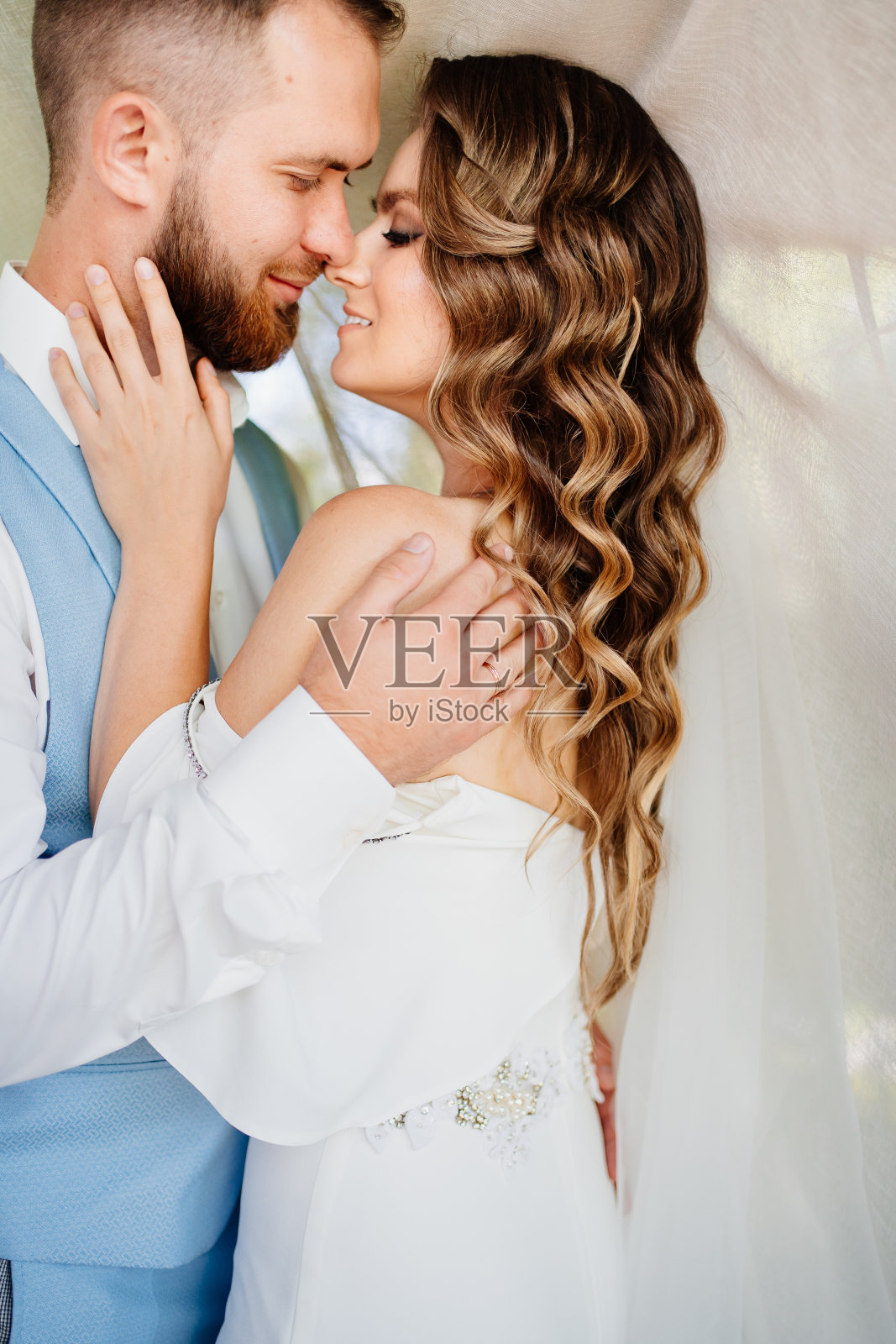 公园里，新婚夫妇站在凉亭的白色帘子旁。照片摄影图片