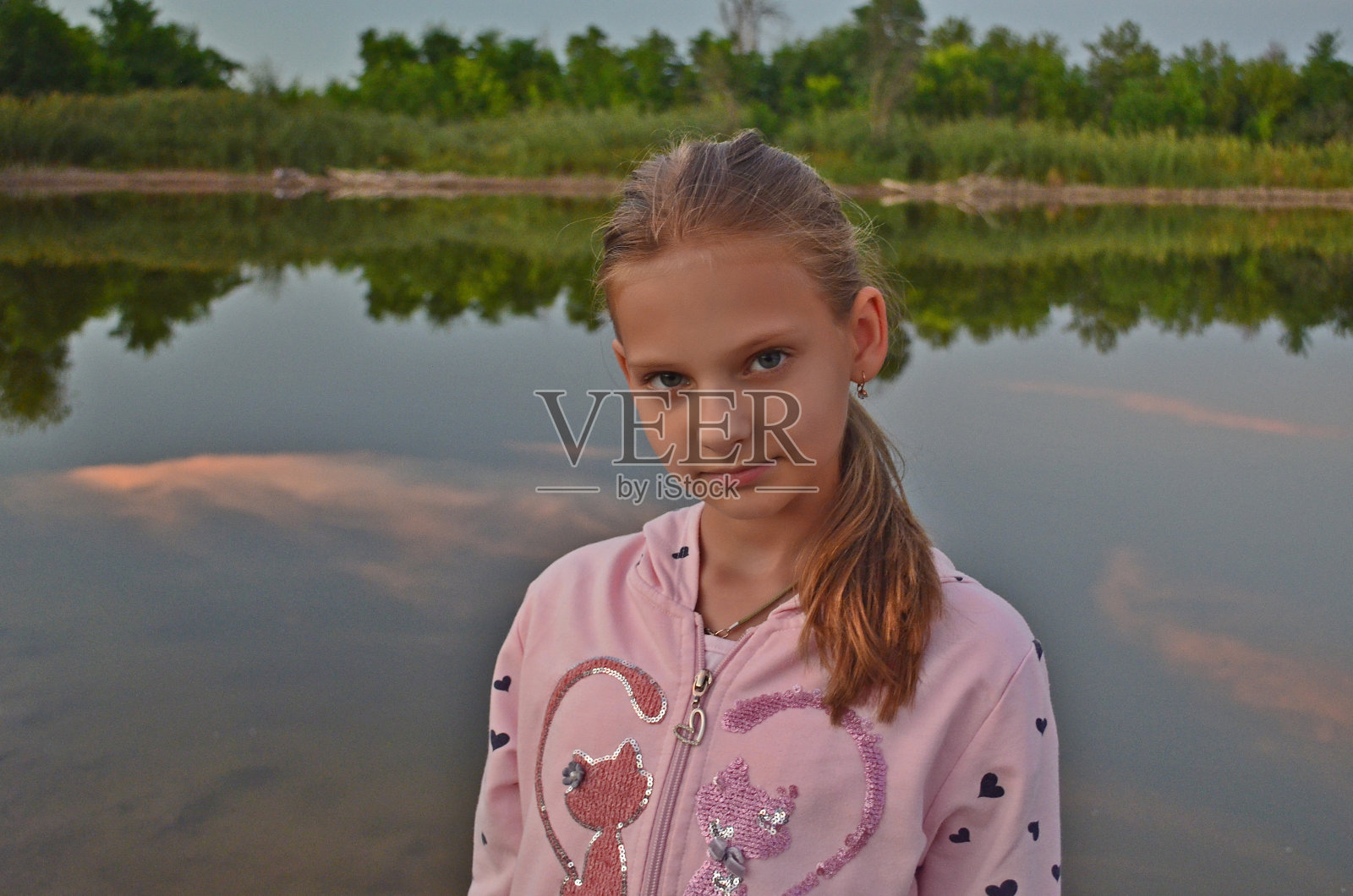 一个十几岁的女孩在日落的湖岸肖像摄影会议。照片摄影图片