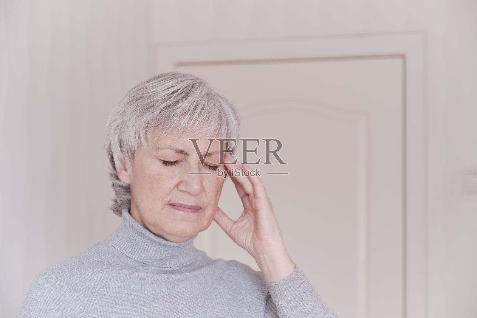 这是一幅特写，特写的是一位留着灰白短发、头痛的老年白人妇女。照片摄影图片