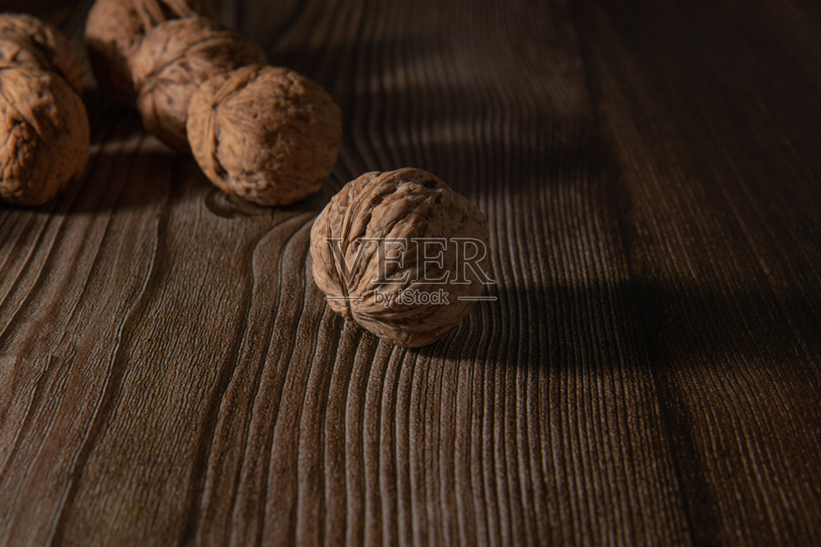 胡桃木紧贴在带有阴影的木质表面上。单色布朗的概念。照片摄影图片