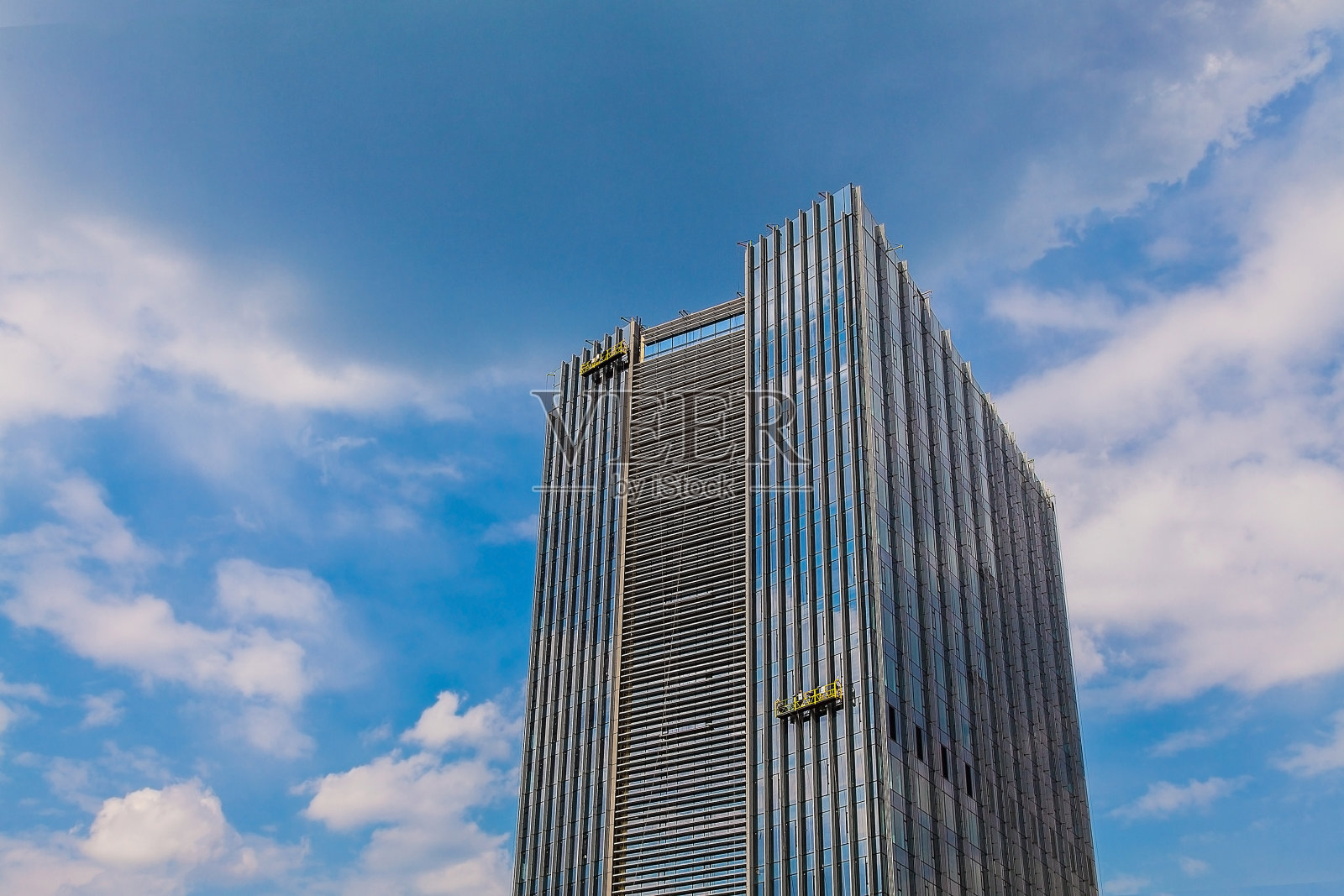 工人们在一个悬挂的摇篮里清洗高层建筑的窗户照片摄影图片