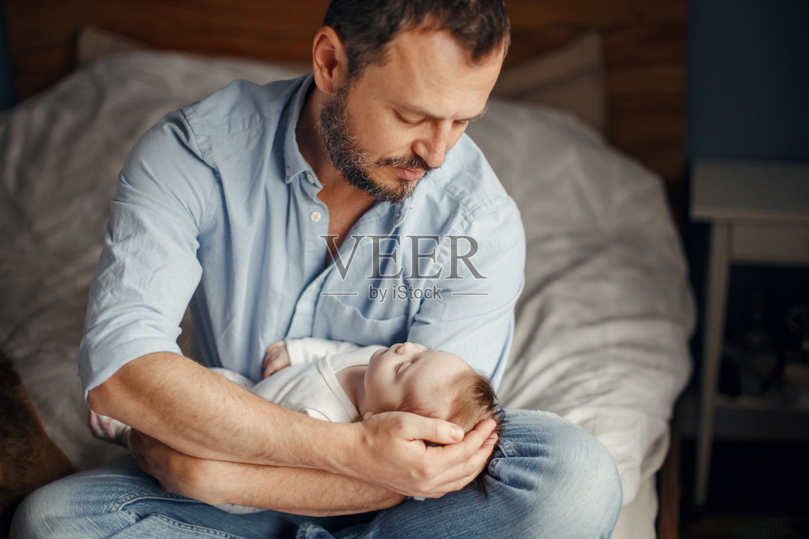 中年白人父亲抱着熟睡的新生女婴。父母手里抱着一个孩子，一个女儿，一个儿子。真正的生活方式父母的父亲时刻。单亲家庭家庭生活。照片摄影图片
