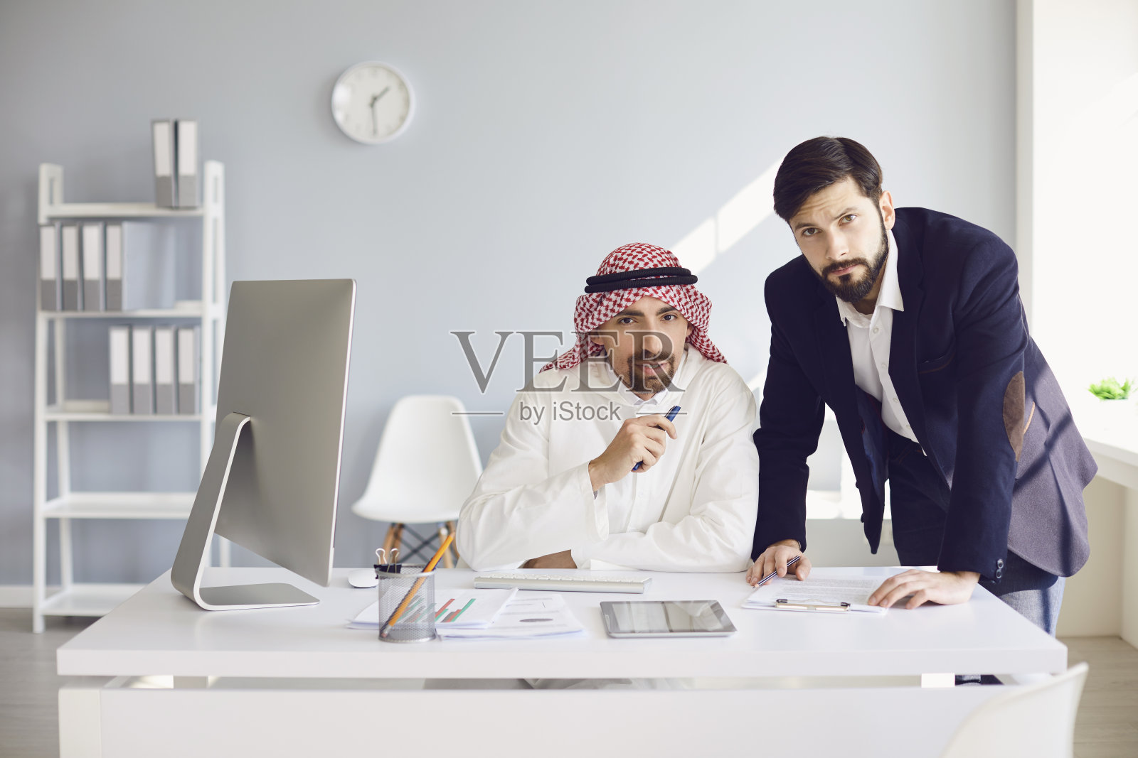 阿拉伯和欧洲商人在白人办公室里自信地工作。照片摄影图片