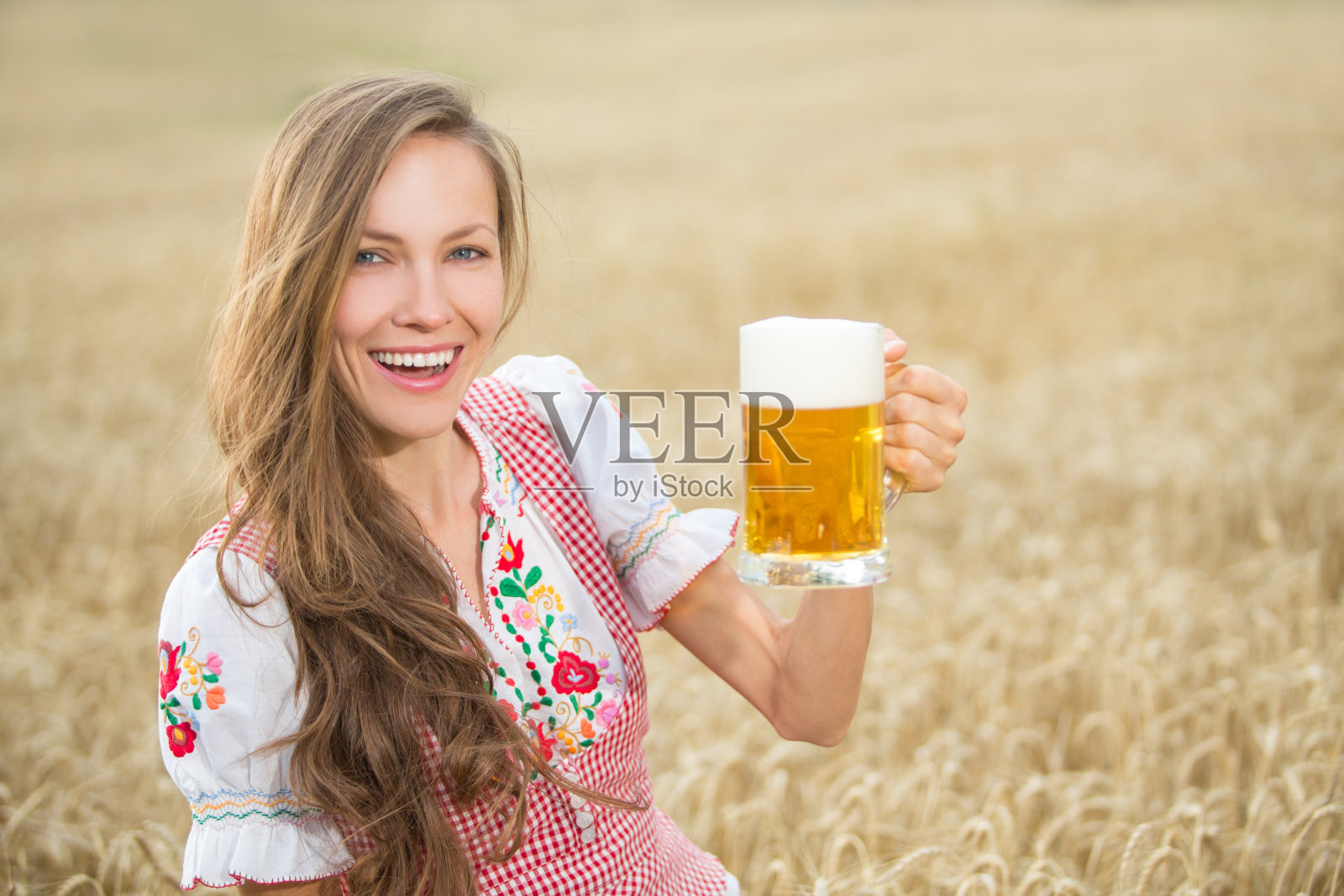 在麦田里喝啤酒的德国女孩照片摄影图片