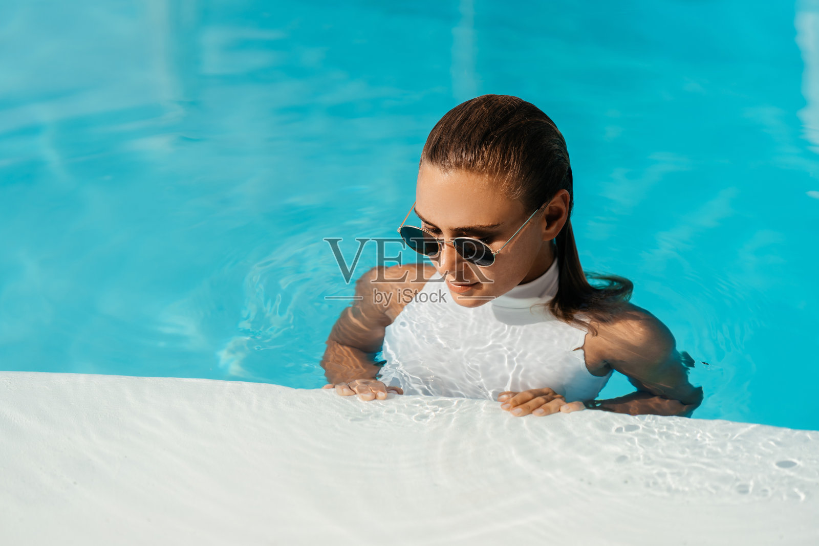 年轻女子暑假在游泳池里放松。照片摄影图片