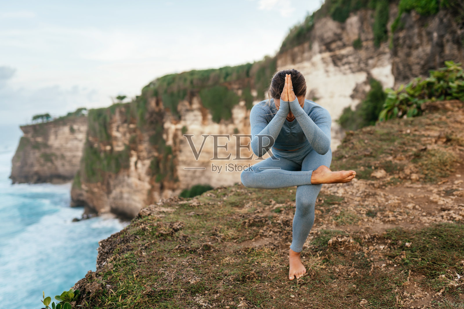 美丽的女人在悬崖上做瑜伽，后面是迷人的海景照片摄影图片