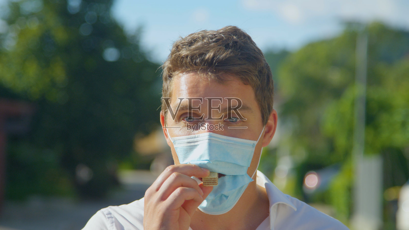 肖像:愚人通过保护面罩上的一个洞吃甜食。照片摄影图片