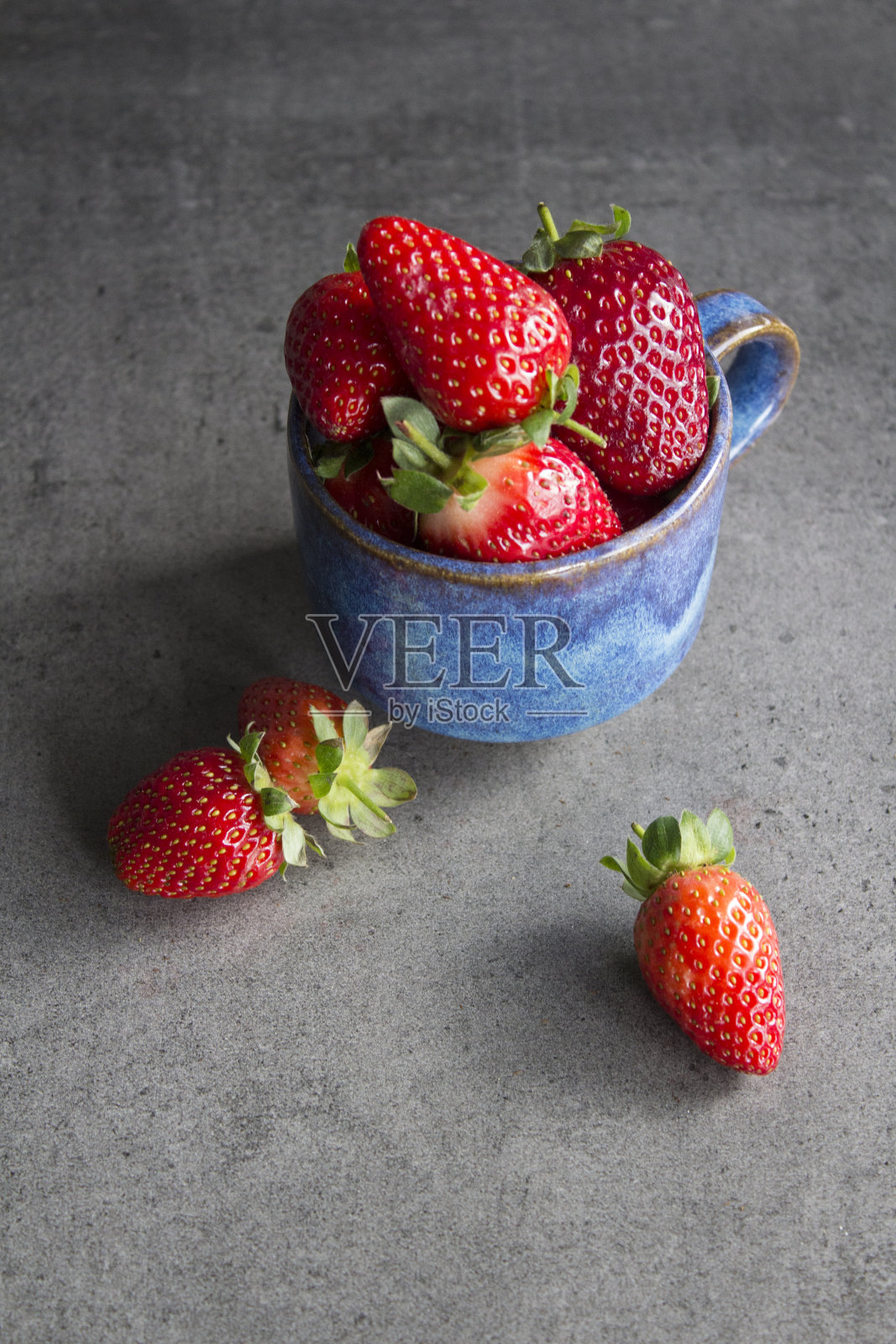 灰色纹理背景上的草莓杯照片摄影图片