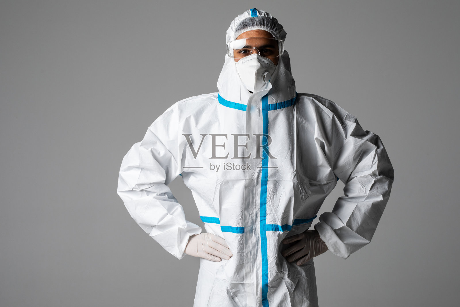 男医生的肖像戴眼镜，防护眼镜在防护服，脸外科口罩在白色的背景。新型冠状病毒大流行的医学卫生保健概念检疫照片摄影图片