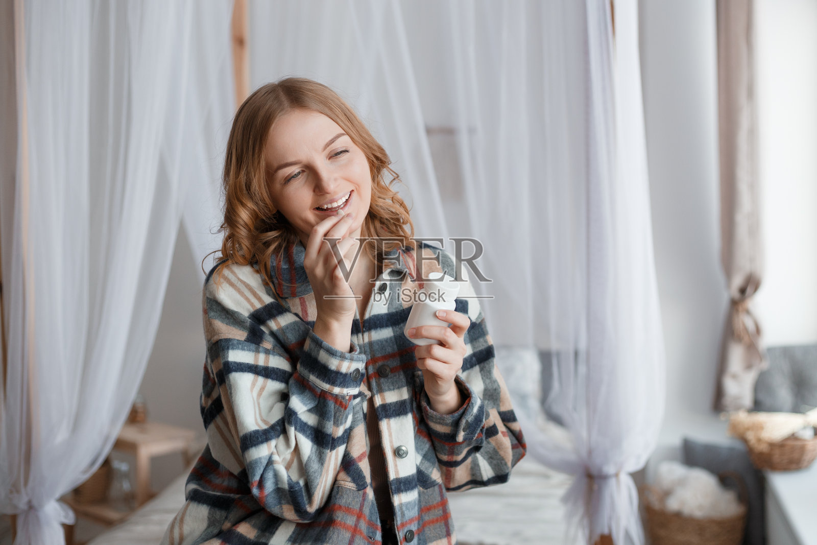 女人服药。美丽的金发女孩在吃药，手里拿着药瓶子。饮食。营养。健康饮食,生活方式。头疼照片摄影图片