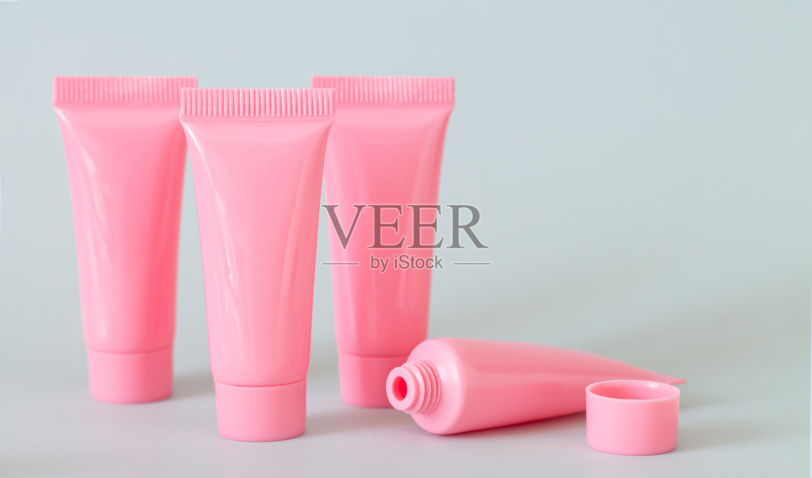 一套粉红色化妆品管在灰色背景特写照片摄影图片