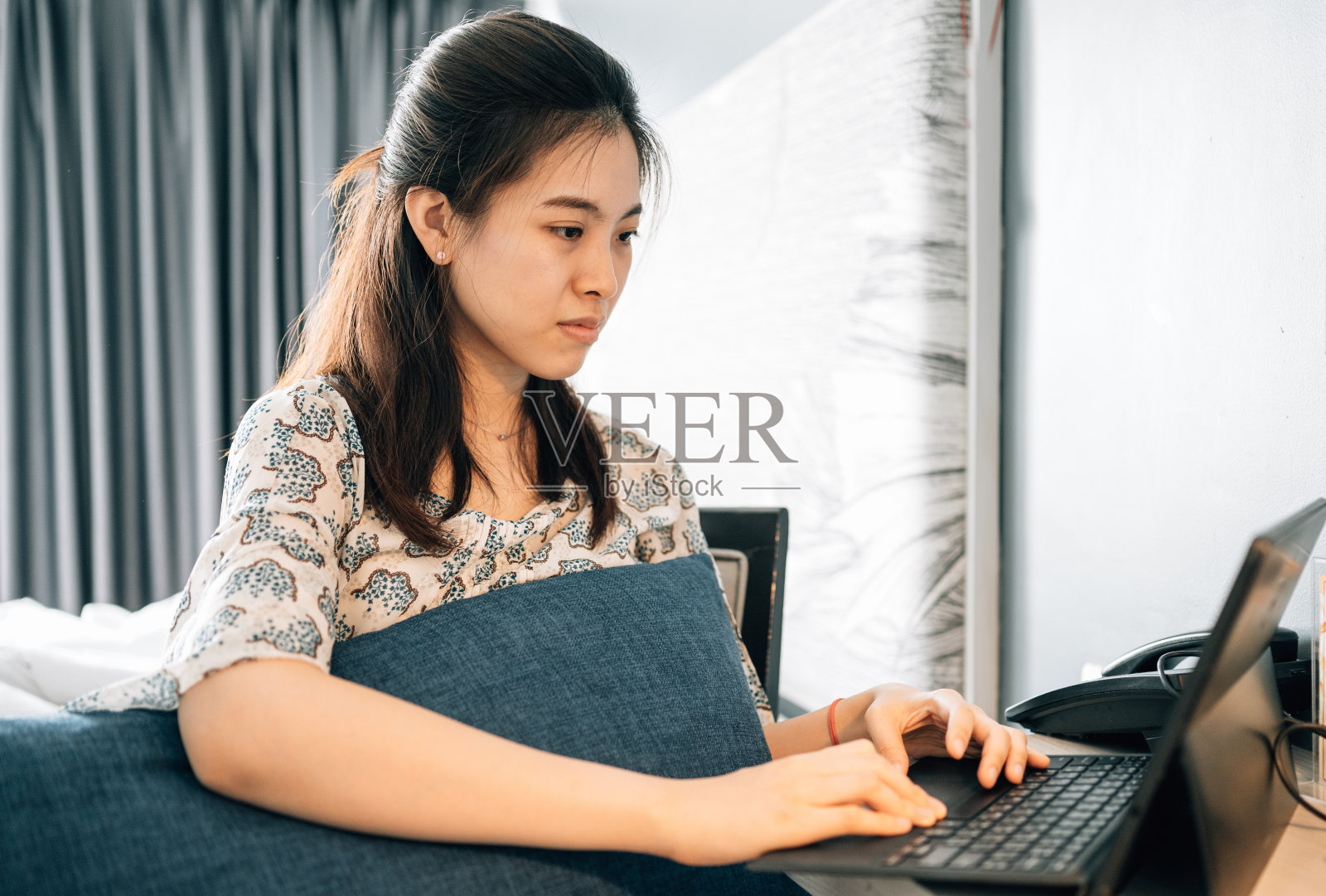 年轻的亚洲女企业家忧心忡忡地看着家里的笔记本电脑，为自己在网上的生意感到压力照片摄影图片