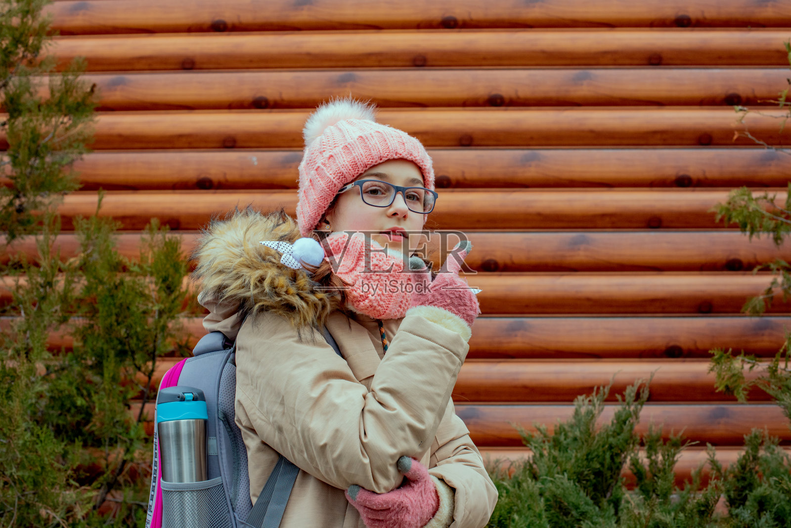 户外肖像可爱的10- 11岁的女孩穿着暖和的夹克。穿着米色夹克的女学生。戴眼镜的少女。照片摄影图片