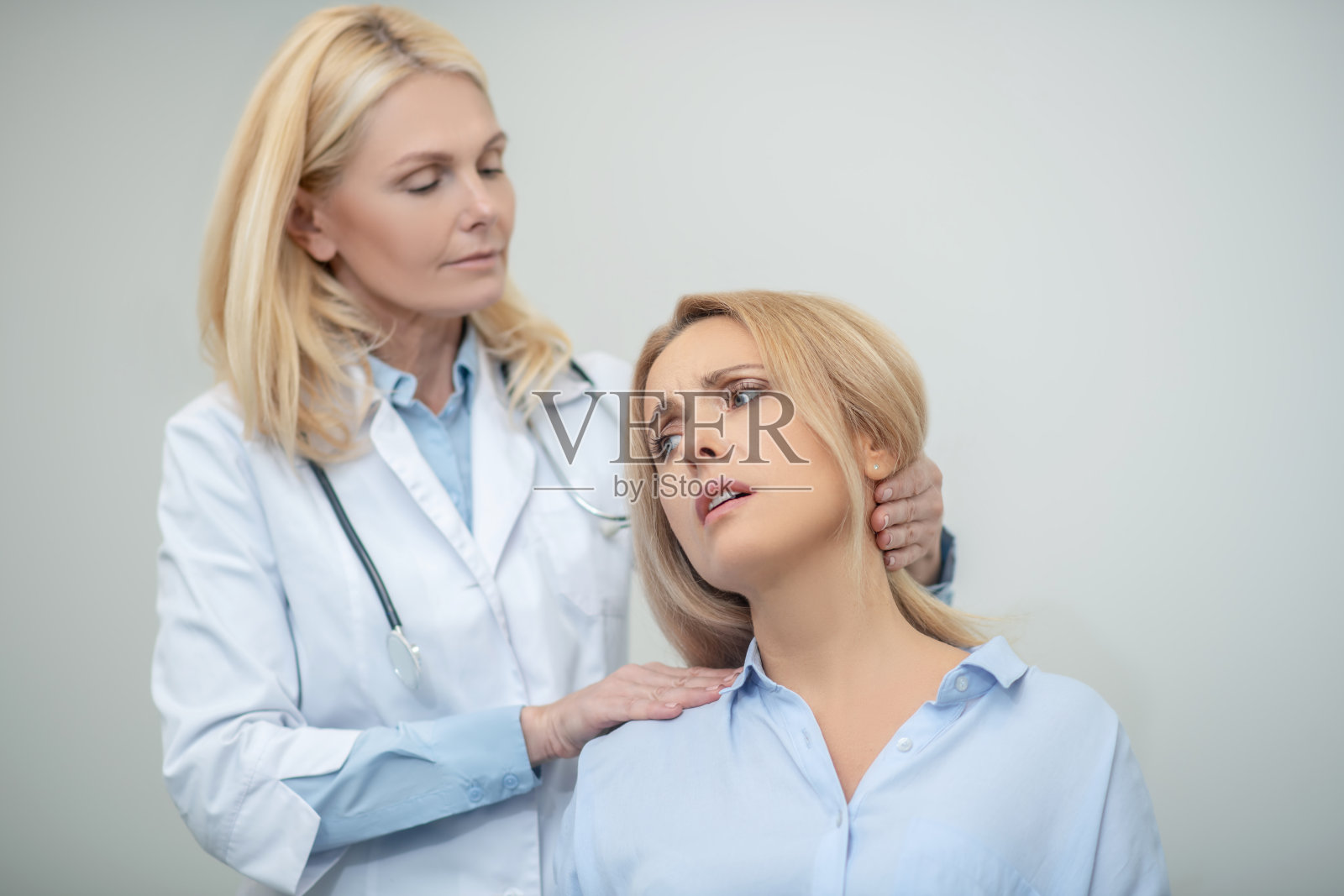 医生歪着头，不幸的女人有疼痛综合症照片摄影图片