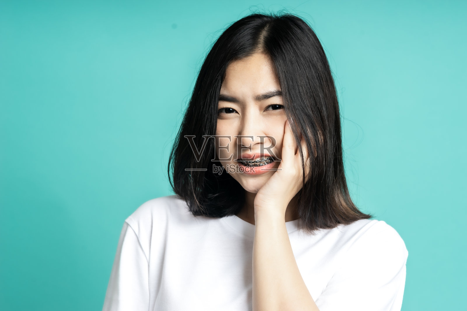 十几岁的女人戴着牙套，她有一个牙痛孤立的背景照片摄影图片