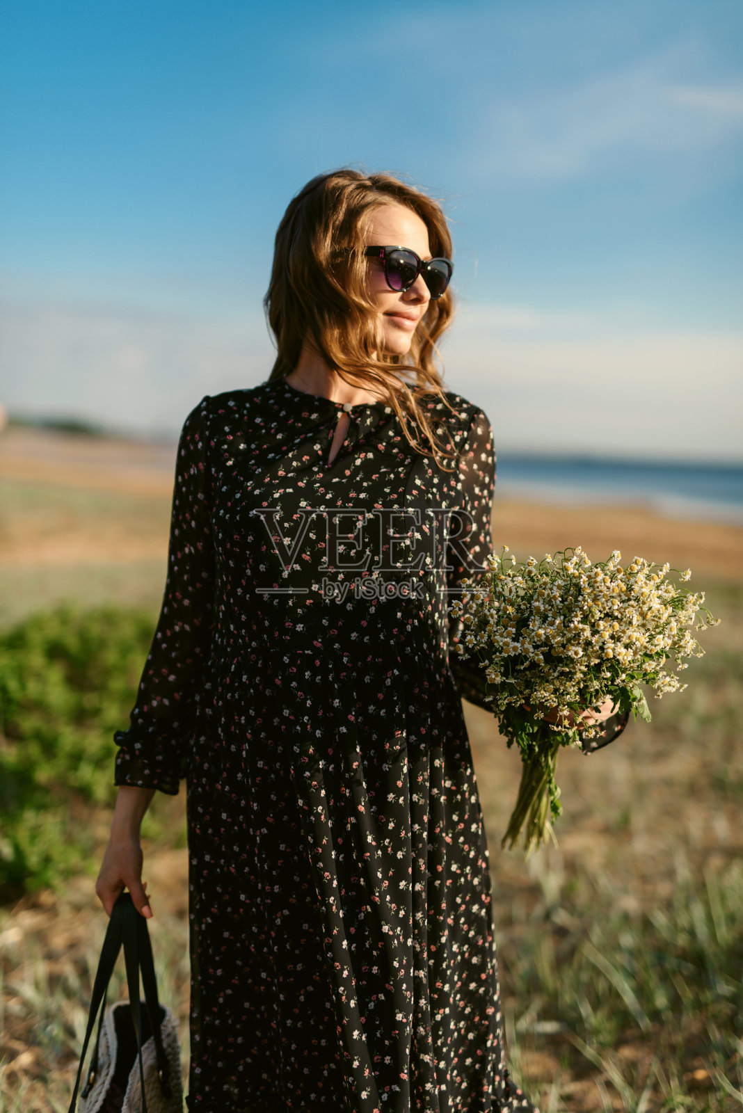 漂亮的年轻孕妇穿着一件轻薄的衣服，手里拿着一束鲜花。等待分娩的孕妇。在妊娠中期和晚期之间照片摄影图片