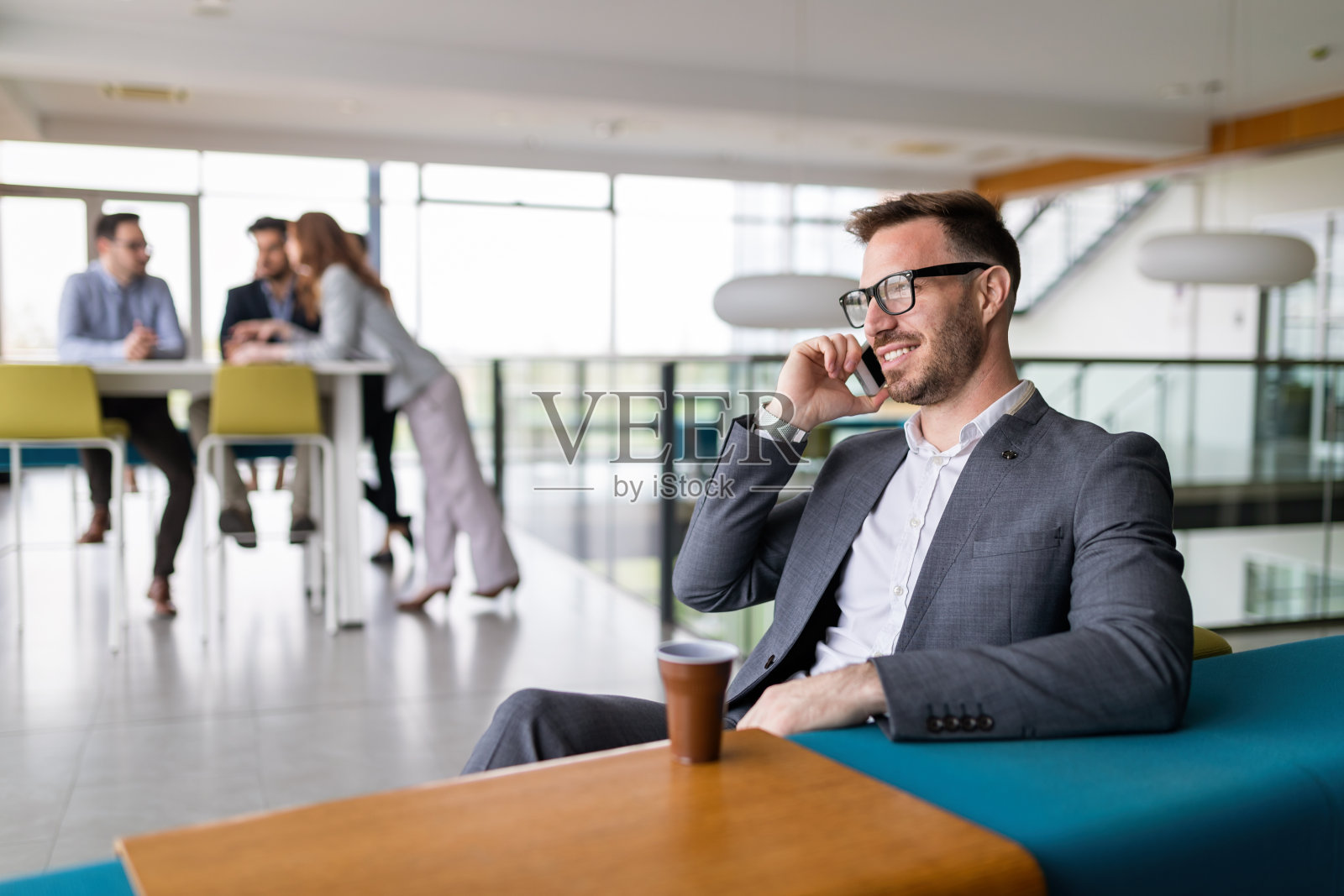 英俊成功的商人在办公室打电话。照片摄影图片