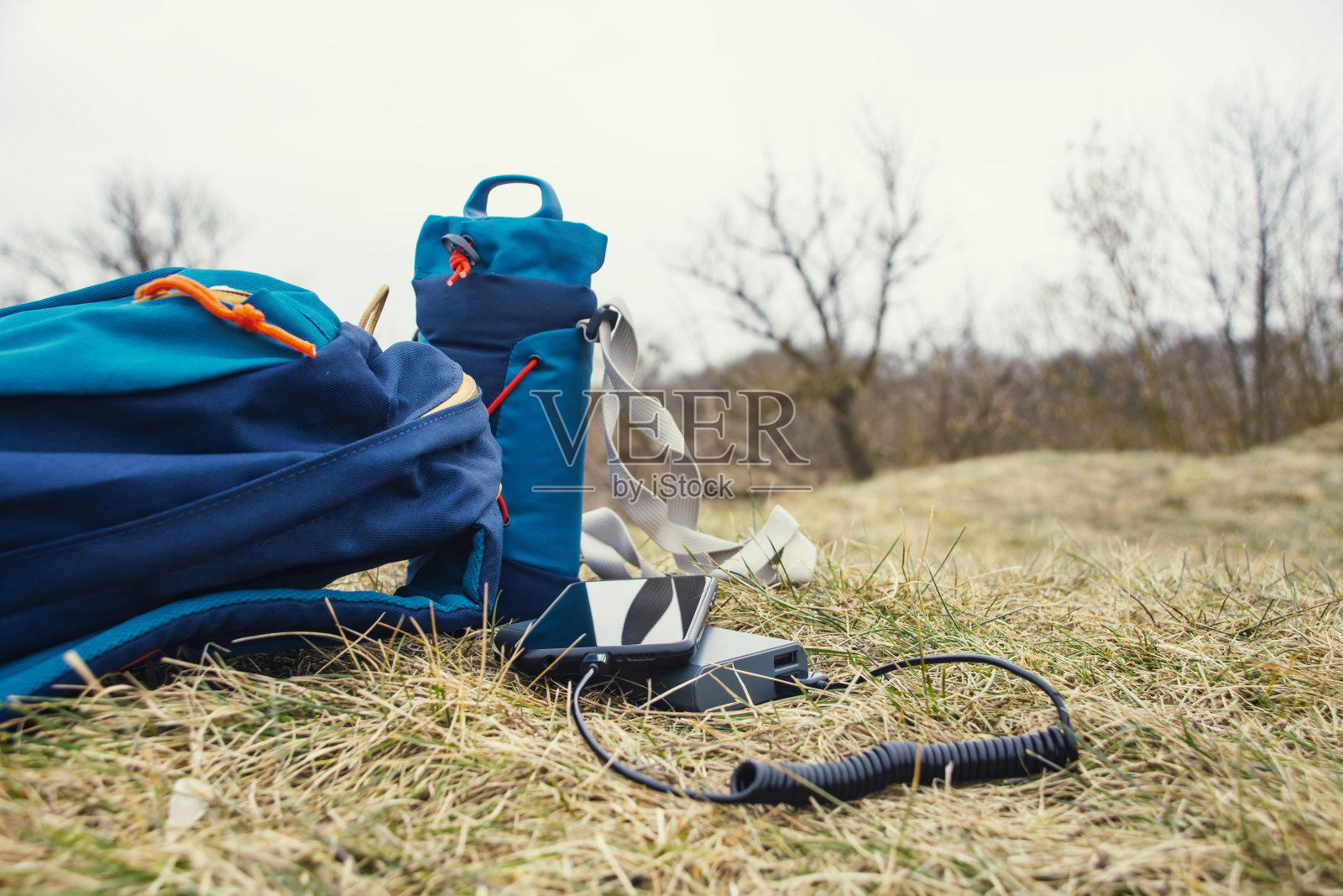 便携式充电器为平板电脑充电。电力银行与电缆，以自然为背景。照片摄影图片