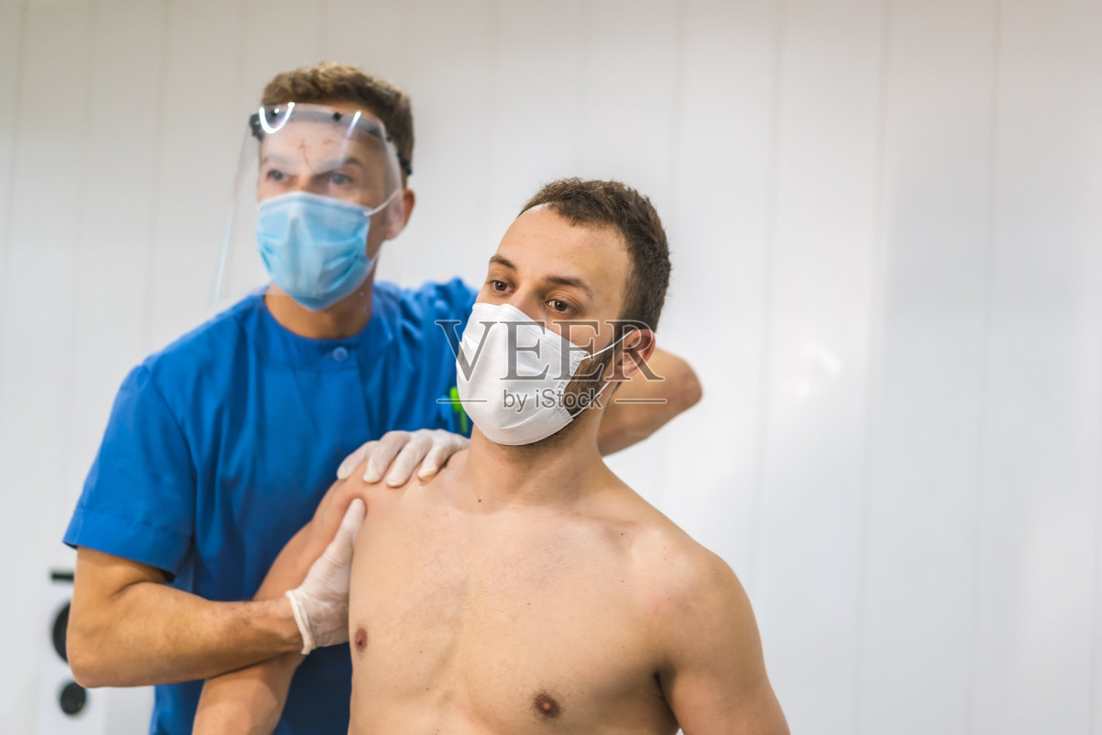 给病人做肩部按摩的理疗师。2019冠状病毒病(COVID-19)大流行的物理治疗和防护措施。整骨疗法,治疗chiromassage照片摄影图片