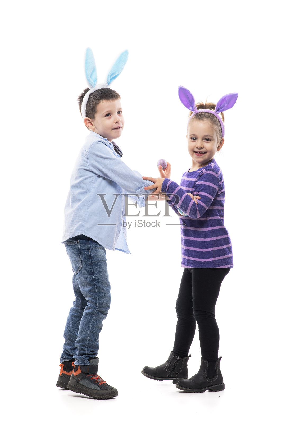 调皮的小弟弟和小妹妹们玩着戴着复活节兔子耳朵的帽子。照片摄影图片