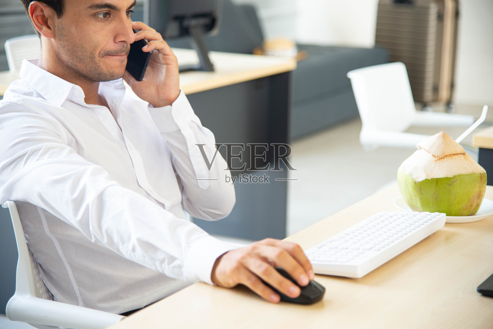 模糊智能和快乐的商人使用智能手机，同时在现代办公室与电脑工作照片摄影图片