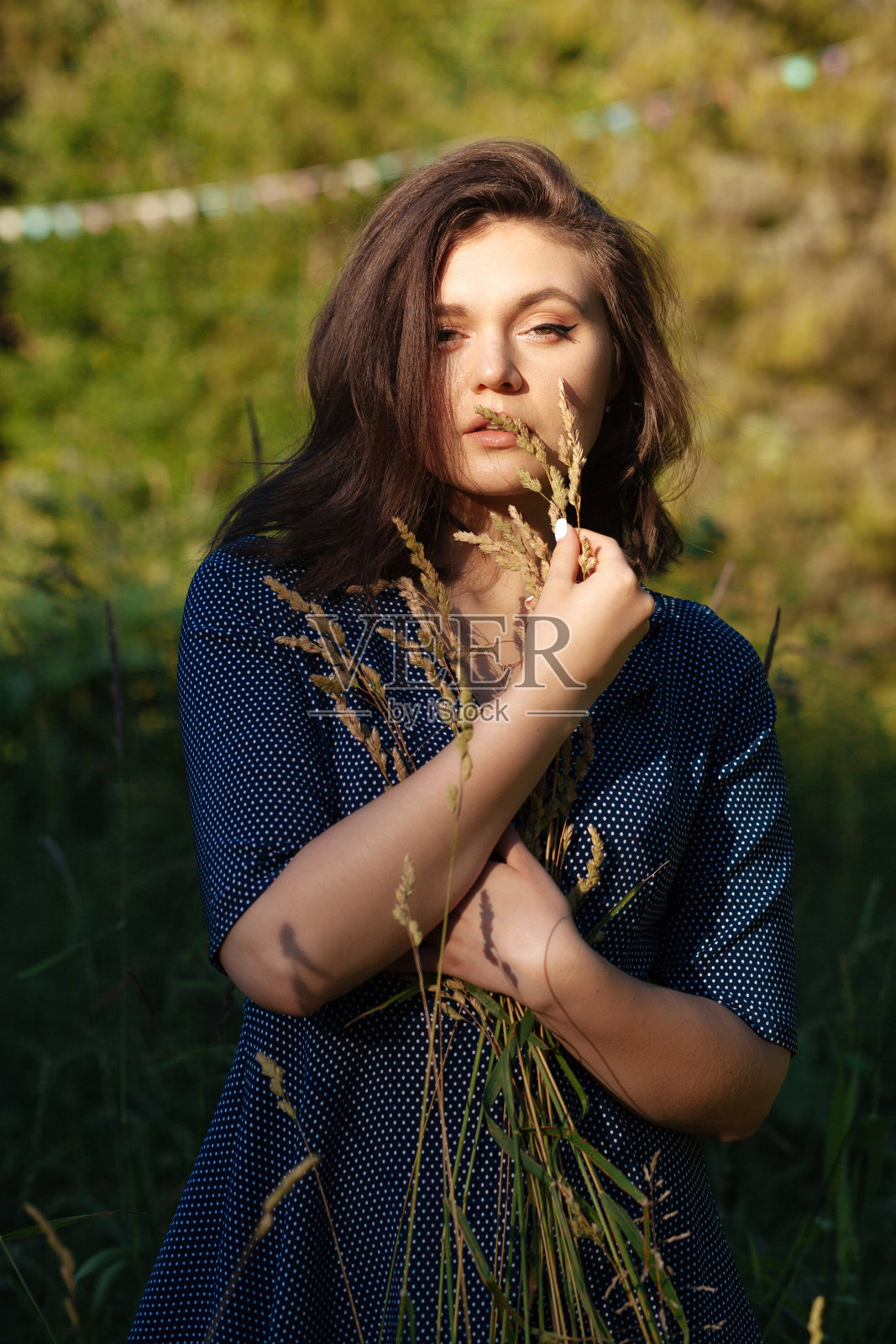 年轻美丽的女人穿着裙子在夏天在高高的草丛中阳光照片摄影图片